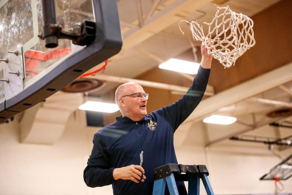 Erie Mason boys basketball coach Kevin Skaggs waves the net after his team clinched the Tri-County Conference championship with a 62-52 win over Britton Deerfield.