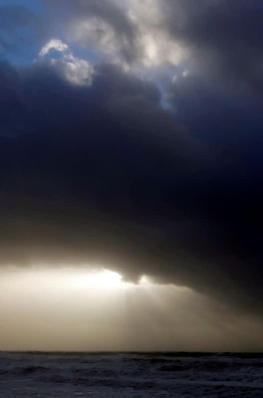 Clouds are pictured as waves break along France's Atlantic coastline at sunset in Lacanau, France, during Carmen storm