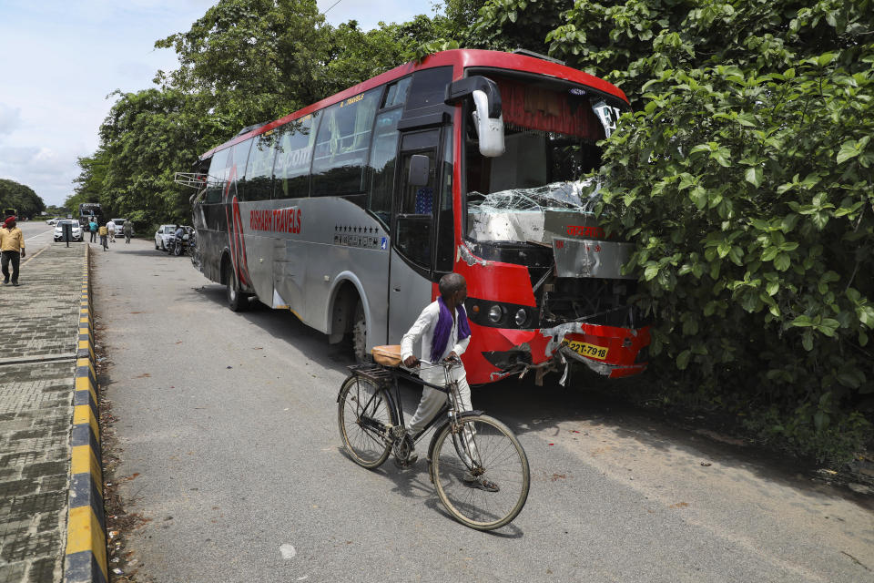 A man pushes his bicycle past a parked bus onto which a truck struck overnight in Barabanki, Uttar Pradesh state, India, Wednesday, July 28, 2021. Police say a truck struck a group of laborers sleeping under the parked bus on the side of a highway in northern India, killing more than a dozen of them. (AP Photo/Sumit Kumar)