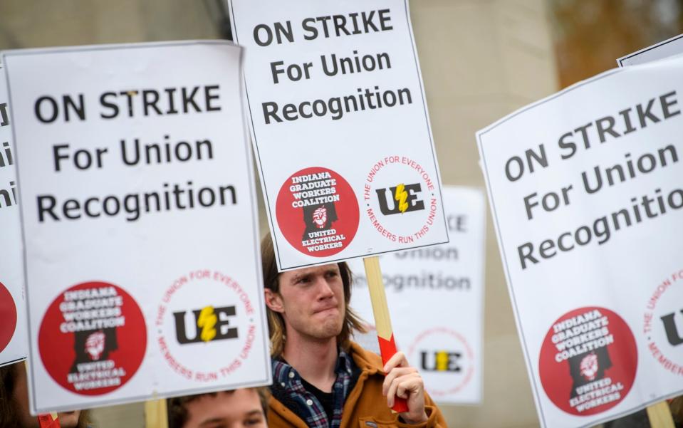 Ryan Webster listens to a speaker with other supporters of the graduate workers strike at the Sample Gates on Wednesday, April 20, 2022.