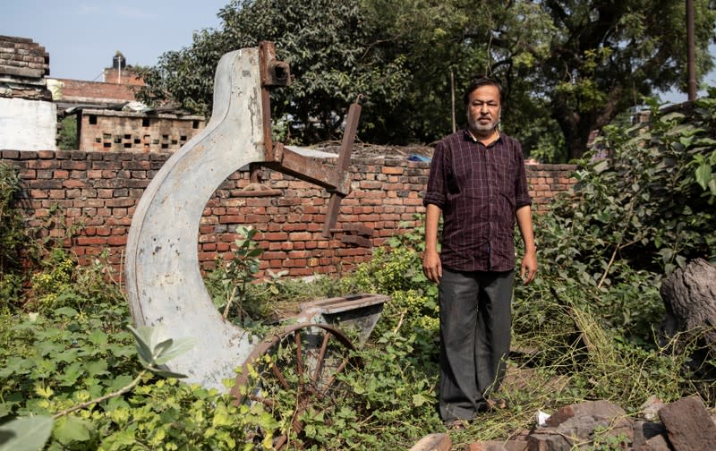 Mohammed Shahid, grandson of Haji Abdul Gaffar, the last imam of Babri mosque, poses in front of a machinery of sawmill which was burnt down by a mob after the demolition of the mosque in Ayodhya