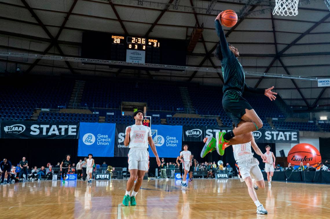 Auburn guard Tyrell Nichols (13) dunks the ball on a fast break as a pair of Eastside Catholic players jog back on defense during the third quarter of a Class 3A quarterfinal game on Thursday, March 2, 2023, in Tacoma, Wash.