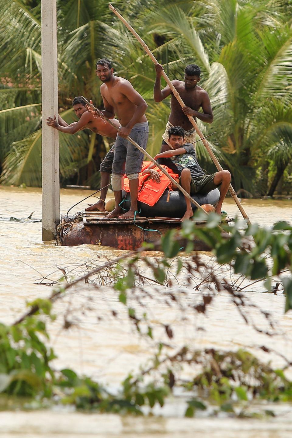 Men row a makeshift raft on a flooded road