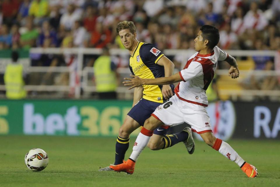 Rayo&#39;s Javier Aquino, right, vies for the ball with Atletico&#39;s Cristian Ansaldi, left, during a Spanish La Liga soccer match between Rayo Vallecano and Atletico Madrid at the Vallecas stadium in Madrid, Spain, Monday, Aug. 25, 2014. (AP Photo/Andres Kudacki)