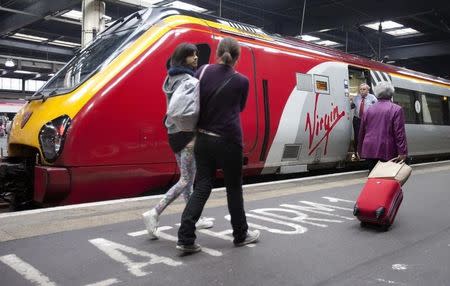 Travellers walk to a Virgin train at Euston rail station in London August 15, 2012. REUTERS/Neil Hall