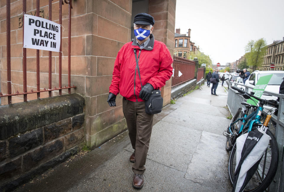A man wearing a face mask arrives to vote at a polling station in Glasgow, Scotland, Thursday May 6, 2021. Scots are heading to the polls to elect the next Scottish Government - though the coronavirus pandemic means it could be more than 48 hours before all the results are counted. (Jane Barlow/PA via AP)