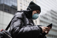 Pedestrian uses her phone while wearing a face mask in Herald Square, Thursday, March 12, 2020, in New York. New York City Mayor Bill de Blasio said Thursday he will announce new restrictions on gatherings to halt the spread of the new coronavirus in the coming days, but he hopes to avoid closing all public events such as Broadway shows. For most people, the new coronavirus causes only mild or moderate symptoms. For some it can cause more severe illness. (AP Photo/John Minchillo)