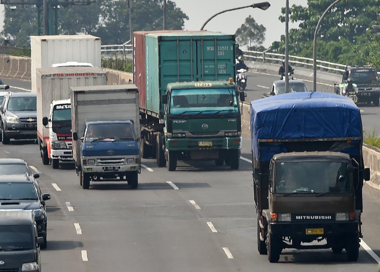 Trucks carrying commodities pass down a highway amongst other vehicles in Jakarta on May 15, 2015.