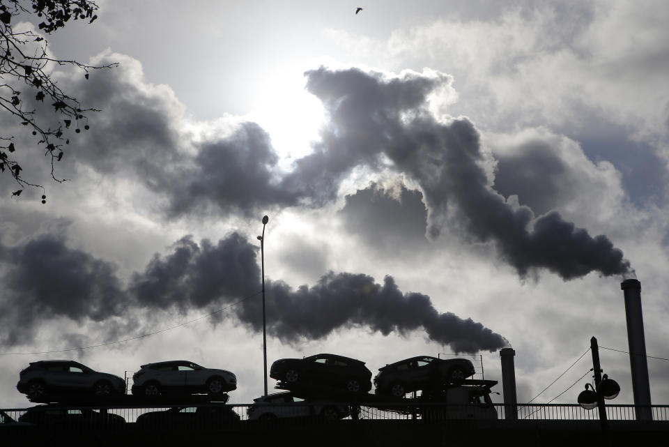 FILE - Smoke rises from a factory as a truck loaded with cars crosses a bridge in Paris, on Nov. 30, 2018. President Emmanuel Macron is to unveil France's approach and means to meet its climate-related commitments within the next seven years as a special government meeting is taking place on Monday Sept. 25, 2023. (AP Photo/Michel Euler, File)