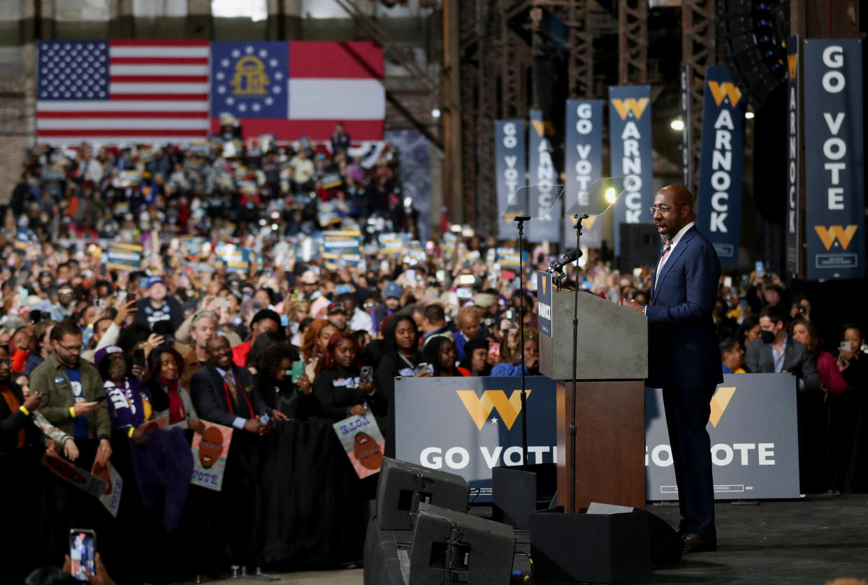 Senator Raphael Warnock speaks from a podium at a rally.