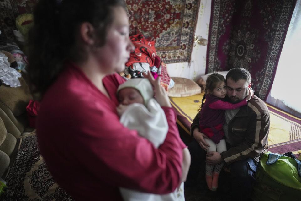 Oleksandr Manha comforts his 4 year-old daughter Sofia as his wife Anastasia Manha, 23, lulls her 2 month-old son Mykyta, where she lives with her family members, after alleged shelling by separatists forces in Novognativka, eastern Ukraine, Sunday, Feb. 20, 2022. Russia is extending military drills near Ukraine's northern borders after two days of sustained shelling along the contact line between Ukrainian soldiers and Russia-backed separatists in eastern Ukraine. The exercises in Belarus, which borders Ukraine to the north, originally were set to end on Sunday. (AP Photo/Evgeniy Maloletka)