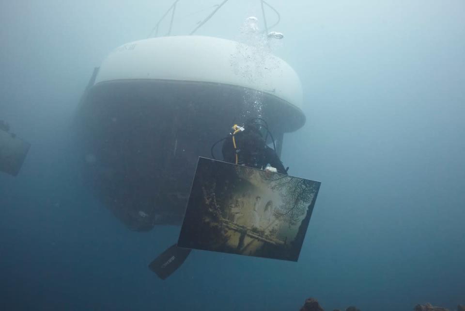 Un buzo transporta una obra de arte del austríaco de Andreas Franke, durante la instalación de la exihibición "The Sinking World", en el mar Caribe.