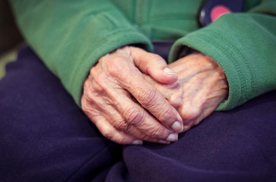 Close-up of the hands of an old Asian Indian woman with wrinkled skin. Depicts loneliness, worry, dementia, and mental health concepts.