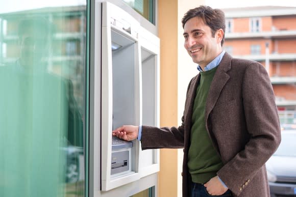 Smiling man using an ATM in a banking center in Italy.