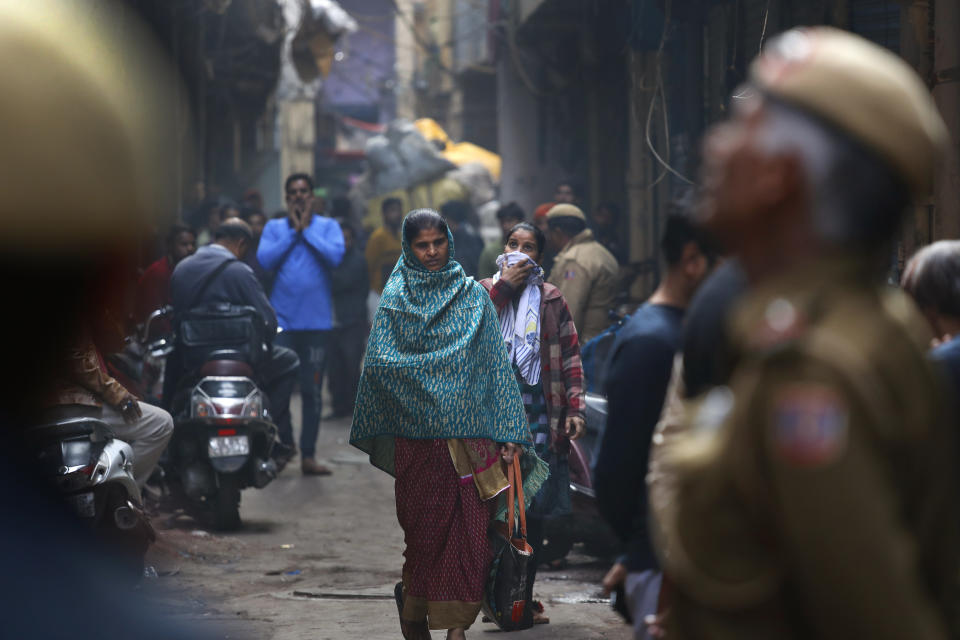Residents walk past a building in an alley which caught fire on Sunday in New Delhi, India, Monday, Dec. 9, 2019. The victims of a devastating factory fire in central New Delhi early Sunday, in which dozens of people died, lived in a dense neighborhood packed with thousands of poor migrant workers from different Indian states forced to live and work in buildings without proper ventilation and prone to fire. (AP Photo/Manish Swarup)