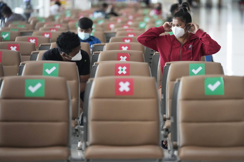 Passengers sit spaced apart while wearing face masks to help curb the spread of the coronavirus at Suvarnabhumi airport in Bangkok, Thailand, Wednesday, July 21, 2021. The Civil Aviation Authority of Thailand has ordered a halt to all domestic flights operating from the most severely affected provinces effective Wednesday. Exceptions are allowed for flights to destinations that are part of a plan that allows vaccinated travelers from abroad to stay for two weeks on popular islands such as Phuket and Samui without quarantine confinement. (AP Photo/Sakchai Lalit)