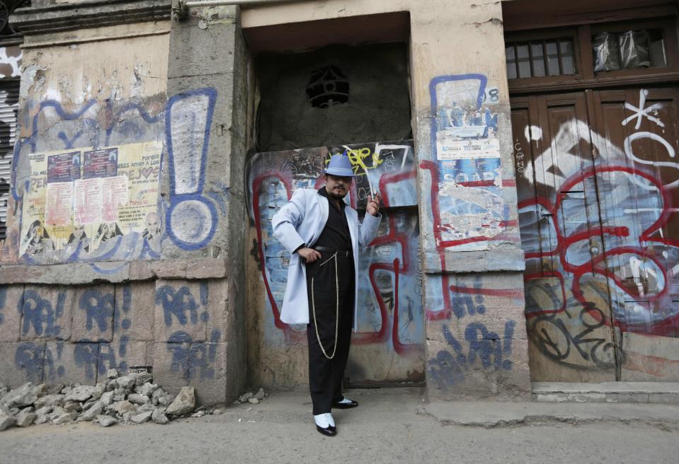 Guardarrama Tapia wears his "Pachuco" outfit while posing for a photograph next to a wall with graffiti in Mexico City