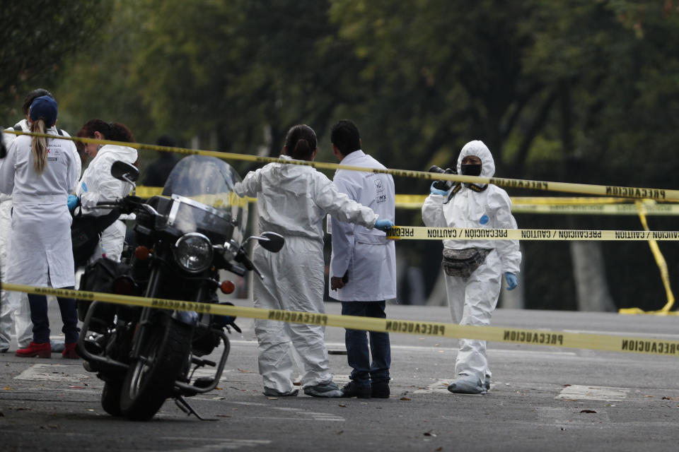 Forensic investigators and police work the scene where security secretary, Omar García Harfuch, was attacked by gunmen in the early morning hours in Mexico City, Friday, June 26, 2020. Heavily armed gunmen attacked and wounded Mexico City's police chief in a brazen operation that left an unspecified number of dead, Mayor Claudia Sheinbaum said Friday. (AP Photo/Rebecca Blackwell)