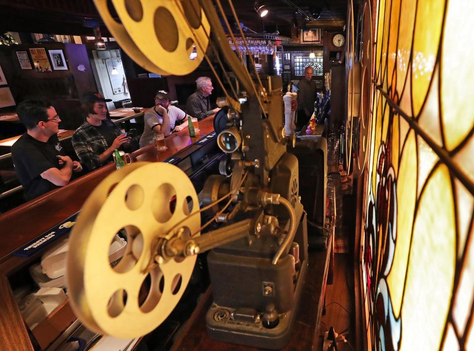 Patrons are framed by one of the many projectors seen around Larry's Main Entrance as they chat over beers.