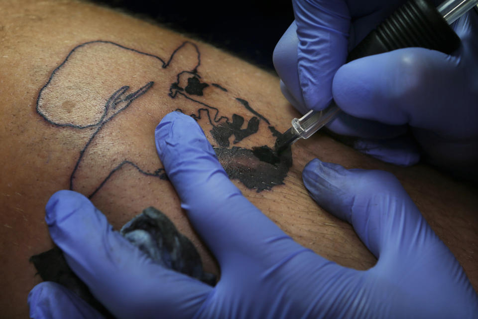 In this Sept. 5, 2018 photo, Lalo Aguayo tattoos an image of Clint Eastwood from the Good the Bad and Ugly movie by Sergio Leone, at the Corona Tattoo parlor in Mexico City. Aguayo, now 35, a public relations specialist and muralist, said a friend convinced him to turn some of his drawings into tattoos. (AP Photo/Marco Ugarte)