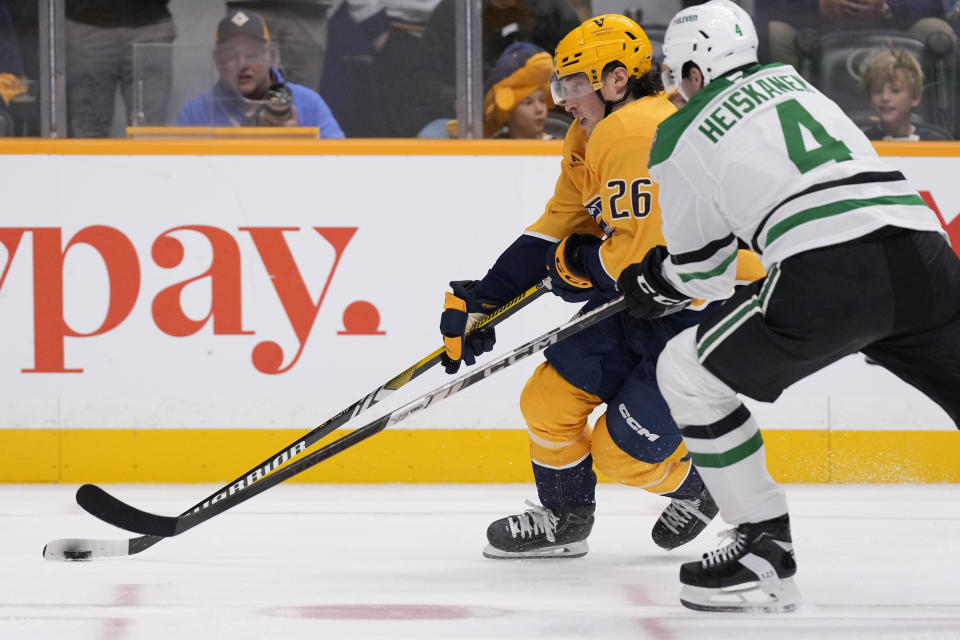 Nashville Predators center Philip Tomasino (26) skates the puck past Dallas Stars defenseman Miro Heiskanen (4) during the second period of an NHL hockey game Thursday, Oct. 10, 2024, in Nashville, Tenn. (AP Photo/George Walker IV)