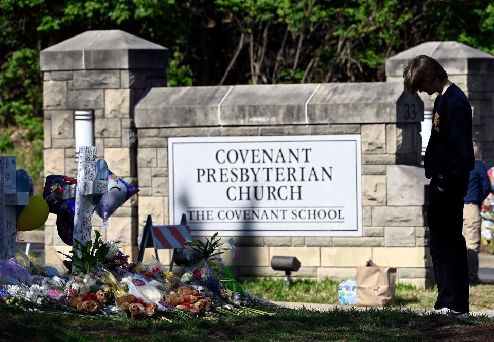 People pay their respects at a makeshift memorial by the entrance of the Covenant School March 30, in Nashville, Tenn., after three children and three school staff members were killed by a former student in a mass shooting.