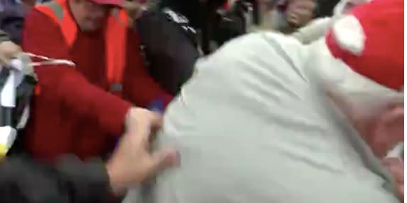 The man wearing a red cap was pushed to the floor at the protest in London (ITV)