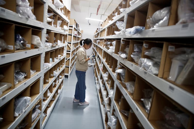 Staff member collects an order from the shelves at the warehouse of the second-hand luxury goods retail platform Plum in Beijing