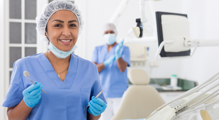 Portrait of smiling hispanic woman dentist preparing tools at modern dental office