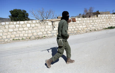 A Turkish-backed Free Syrian Army fighter holds a weapon as he walks north of Afrin, Syria March 17, 2018. REUTERS/Khalil Ashawi