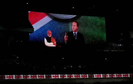 India's Prime Minister Narendra Modi and Britain's Prime Minister David Cameron are seen on a large screen as they stand on stage during an event at Wembley Stadium, in London, November 13, 2015. REUTERS/Suzanne Plunkett