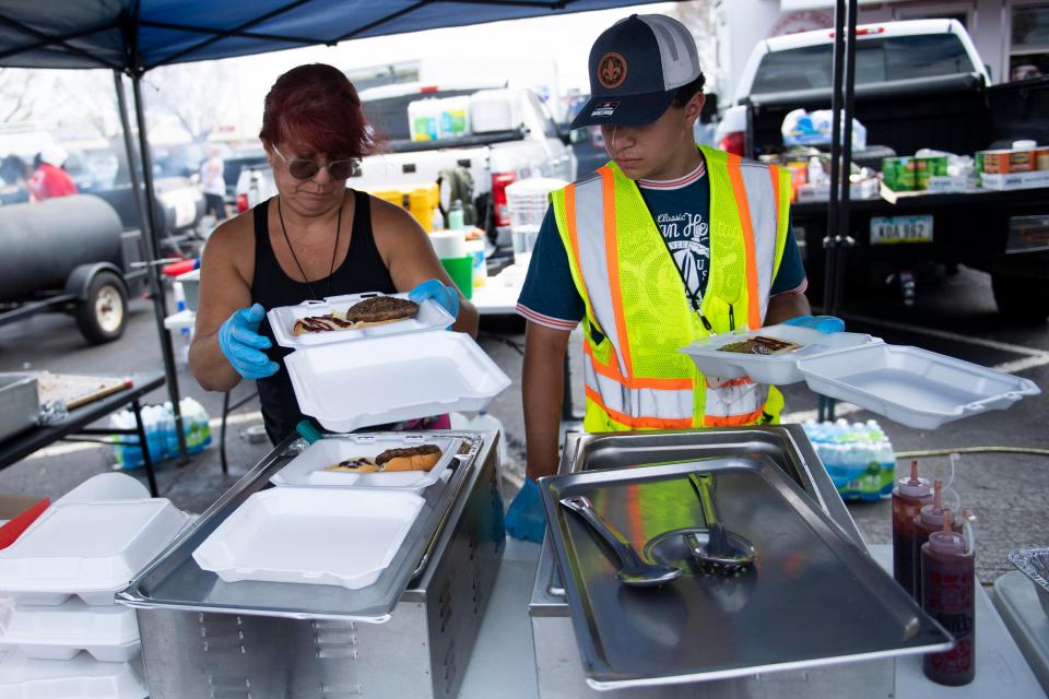 Volunteers Zenaida Robles, left, and Michael Castro, help serve meals for Willie Ray's Q Shack of Cedar Rapids, Iowa, on Sunday, Oct. 9, 2022. Willie Ray Fairley has set up three smokers and is making meals to feed people impacted by Hurricane Ian.