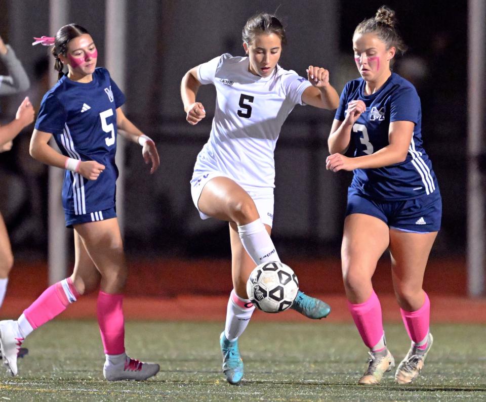 Elena Giordano of Martha's Vineyard kicks the ball between Karlie Monteiro (5) and Fiona Moore (3) of Monomoy.