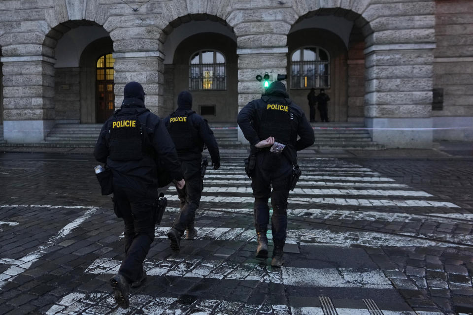 Policemen walk towards the building of Philosophical Faculty of Charles University Prague, Czech Republic, Friday, Dec. 22, 2023. A lone gunman opened fire at a university on Thursday, killing more than a dozen people and injuring scores of people. (AP Photo/Petr David Josek)