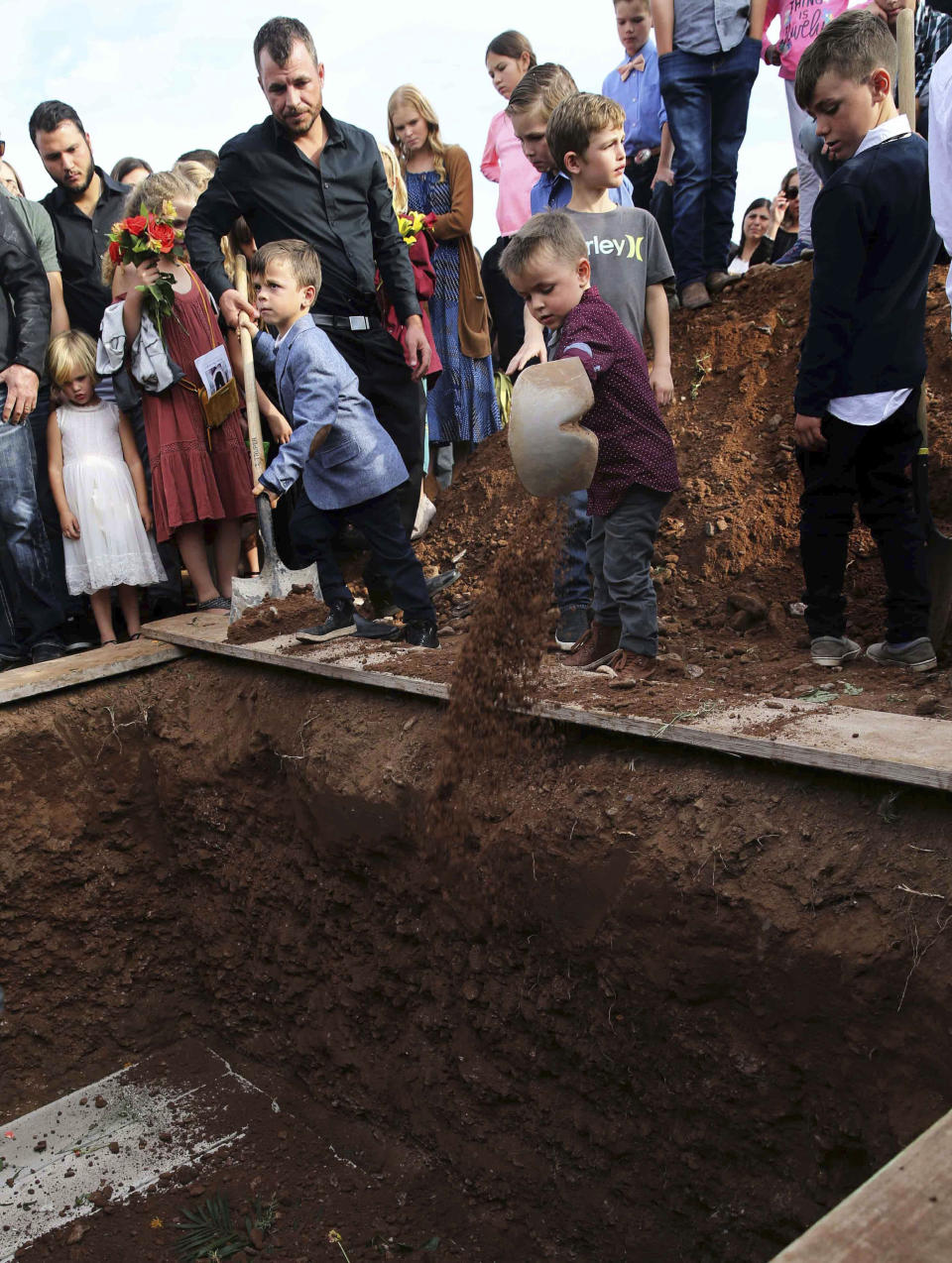 Children shovel dirt into the grave that contains the remains of Christina Langford Johnson the last victim of a cartel ambush that killed nine American women and children earlier this week, during a burial service in Colonia LeBaron, Mexico, Saturday, Nov. 9, 2019. In the attack Monday, Langford Johnson jumped out of her vehicle and waved her hands to show she was no threat to the attackers and was shot twice in the heart, community members say. Her daughter Faith Marie Johnson, 7 months old, was found unharmed in her car seat. (AP Photo/Marco Ugarte)