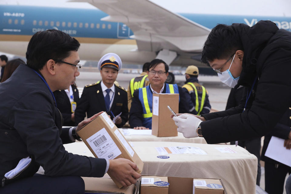 Vietnamese officials examine a carton box with human remains at the tarmac of the Noi Bai airport in Hanoi, Vietnam, Saturday, Nov. 30, 2019. The last remains of the 39 Vietnamese who died while being smuggled in a truck to England last month have been repatriated to their home country. (Lam Khanh/VNA via AP)