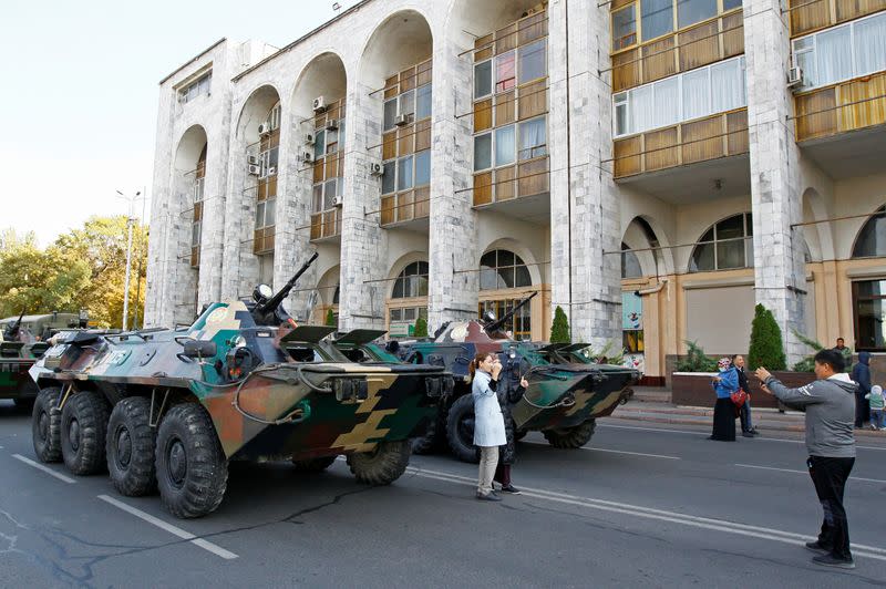 People pose for a picture next to armoured personnel carriers in Ala-Too Square in Bishkek