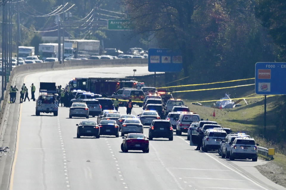 Emergency personnel work at the scene of a helicopter crash on the side of Interstate 77 South in Charlotte, N.C., Tuesday, Nov. 22, 2022. Authorities said two people died. ( (Jeff Siner/The Charlotte Observer via AP)