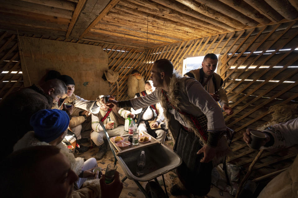 Participants, dressed in traditional costumes, eat and drink while celebrating the Malanka festival in the village of Krasnoilsk, Ukraine, Friday, Jan. 14, 2022. (AP Photo/Ethan Swope)