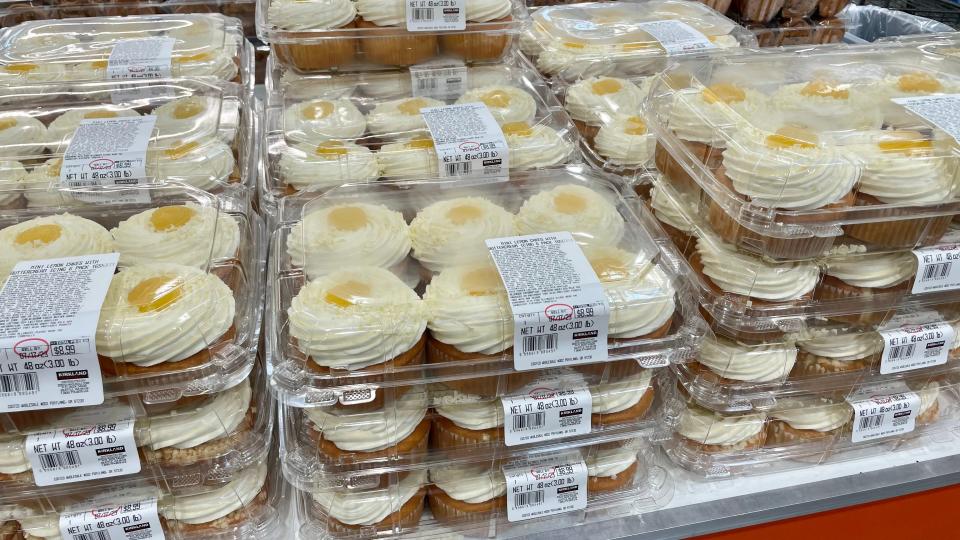 Display of plastic Kirkland Signature lemon cake containers with six frosted cakes in each container at a Costco