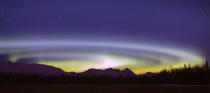 An Aurora Borealis spins above the Talkeetna Range and a hay field on Farm Loop Road near Palmer, Alaska, on Friday, Feb. 29, 2008. The center of the circular corona, usually near Earth's north pole sometimes fluctuates further south and can be seen from a lower latitude as in this instance. (AP Photo/Bob Martinson)