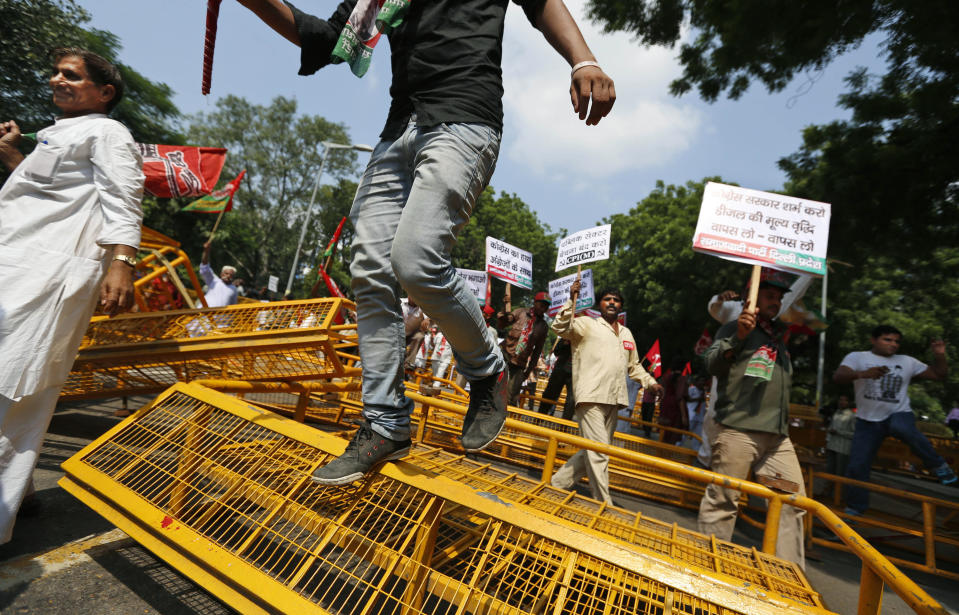 Activists of various left parties along with Samajwadi Party members jump over barricades as they try to get detained by police during a protest in New Delhi, India,Thursday, Sept. 20, 2012. Angry demonstrators disrupted trains Thursday and forced some shops and schools to close in a partly successful national strike protesting a government decision to cut fuel subsidies and open India's huge retail market to foreign companies. (AP Photo/Saurabh Das)