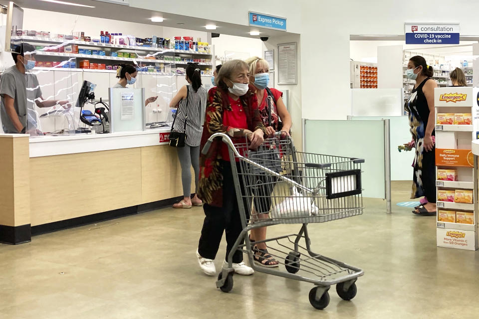 FILE - People wear mask as they shop and wait on line at a Walgreens in Wheeling, Ill., on Aug.18, 2021. A rush of vaccine-seeking customers and staff shortages are squeezing drugstores around the country. That has led to frazzled workers and even temporary pharmacy closures. (AP Photo/Nam Y. Huh, File)