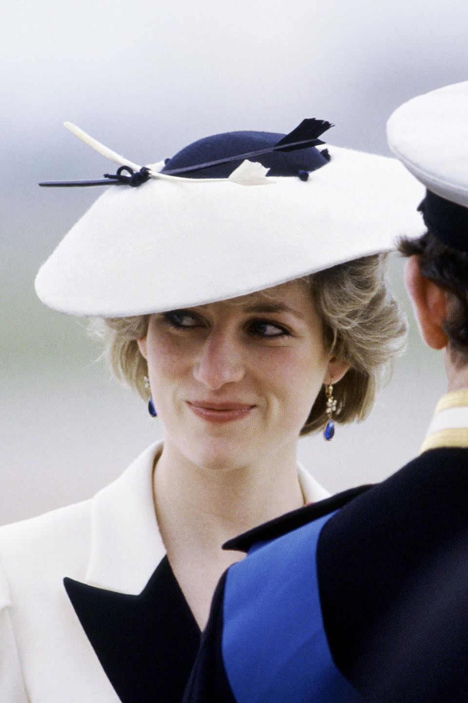 <p>At Heathrow Airport in an intricate navy-and-white saucer hat.</p>