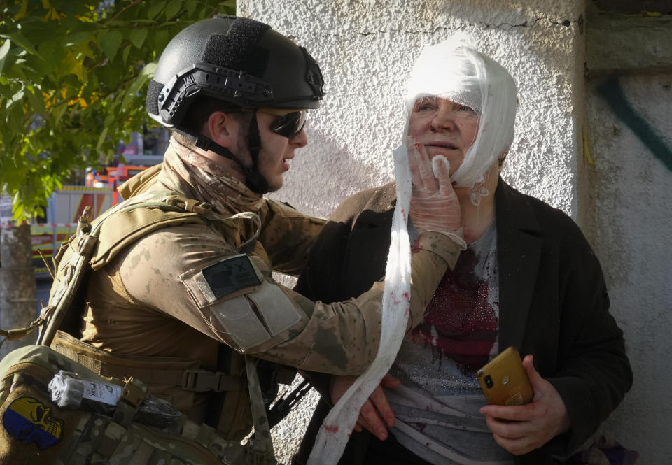 An injured woman receives medical treatment at the scene of Russian shelling, in Kyiv, Ukraine, Monday, Oct. 10, 2022. Multiple explosions rocked Kyiv early Monday following months of relative calm in the Ukrainian capital. Kyiv Mayor Vitali Klitschko reported explosions in the city's Shevchenko district, a large area in the center of Kyiv that includes the historic old town as well as several government offices. (AP Photo/Efrem Lukatsky)