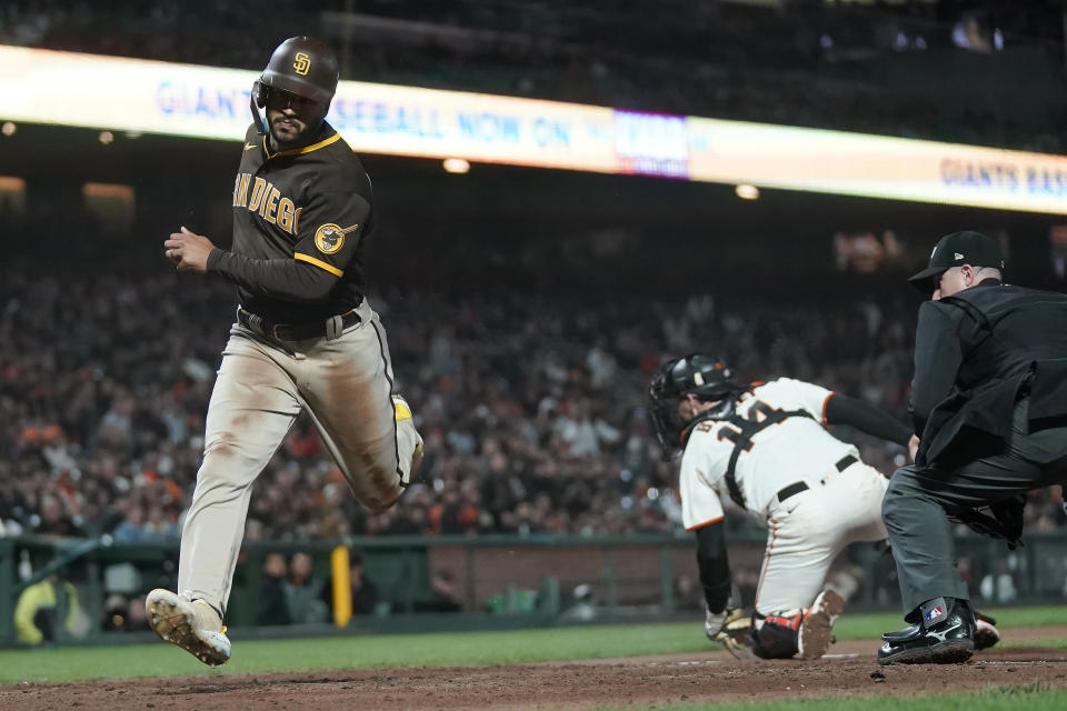 San Diego Padres' Trent Grisham, left, scores past San Francisco Giants catcher Patrick Bailey during the 10th inning of a baseball game in San Francisco, Wednesday, Sept. 27, 2023. (AP Photo/Jeff Chiu)