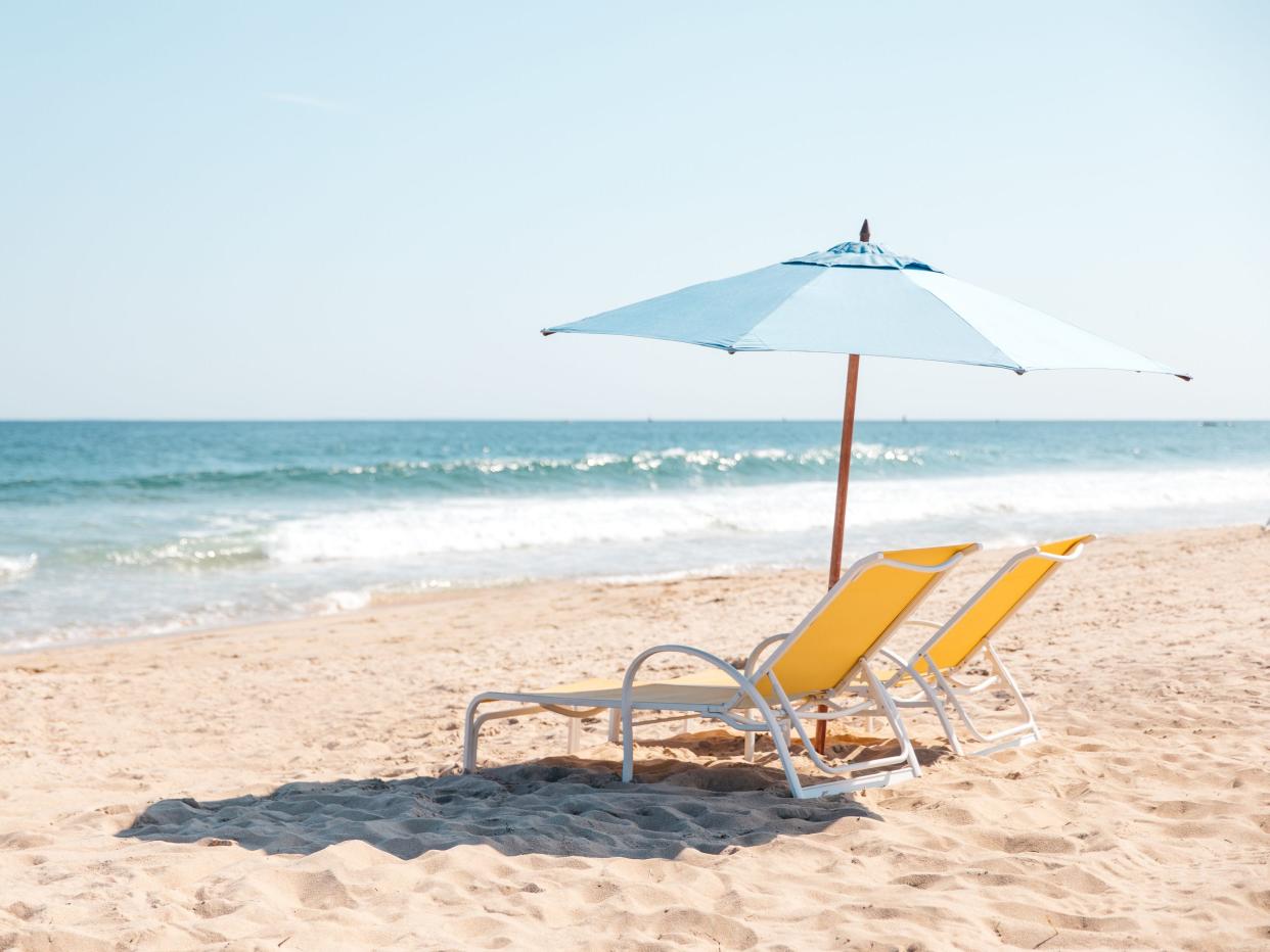 Chairs and an umbrella facing the ocean on the beach in Westerly, Rhode Island at Ocean House Hotel.