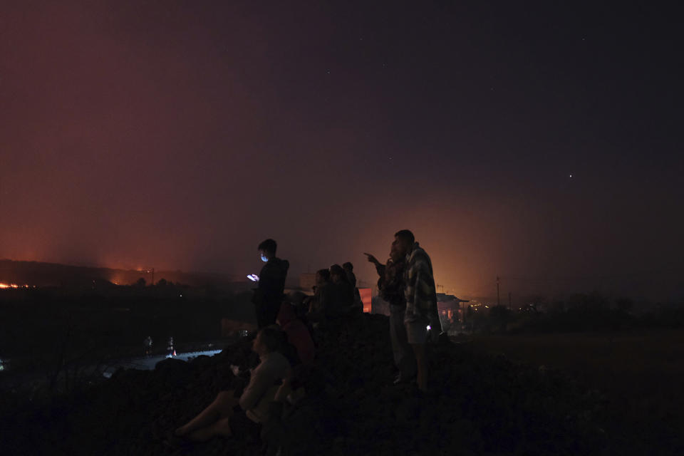 People look across to a volcano as it continues to erupt on the Canary island of La Palma, Spain on Saturday Oct. 16, 2021. Officials say there is no sign that a volcanic eruption on the Spanish island of La Palma is coming to an end, one month after it began. The volcano on one of the Canary Islands off northwest Africa has so far destroyed more than 1,800 buildings, mostly homes. (AP Photo/Daniel Roca)