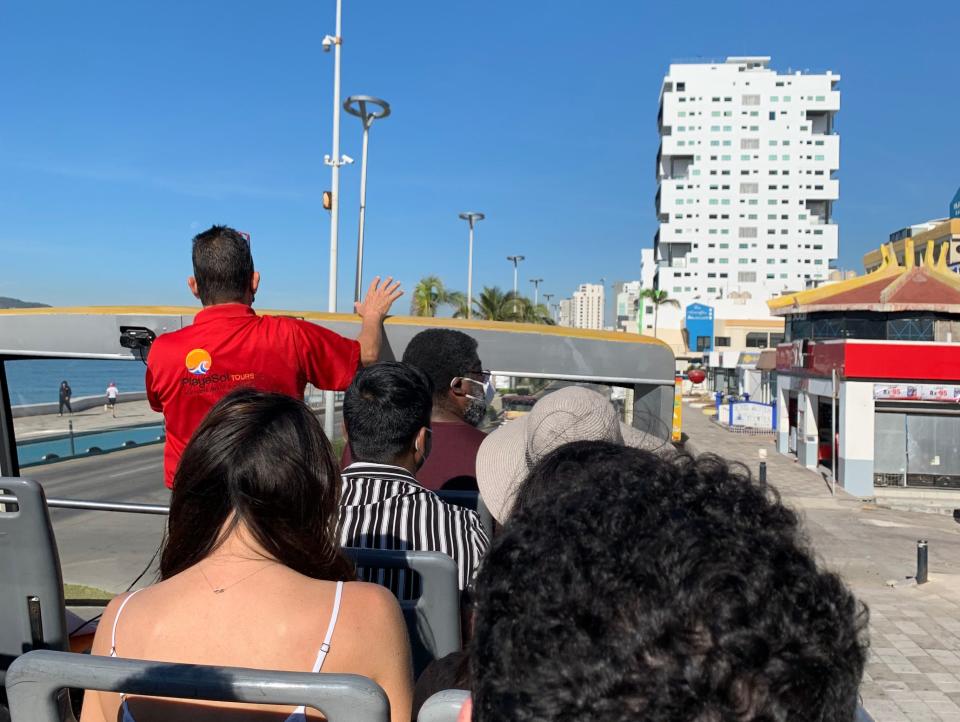tour bus — guide wearing red shirt talking to bus full of tourists