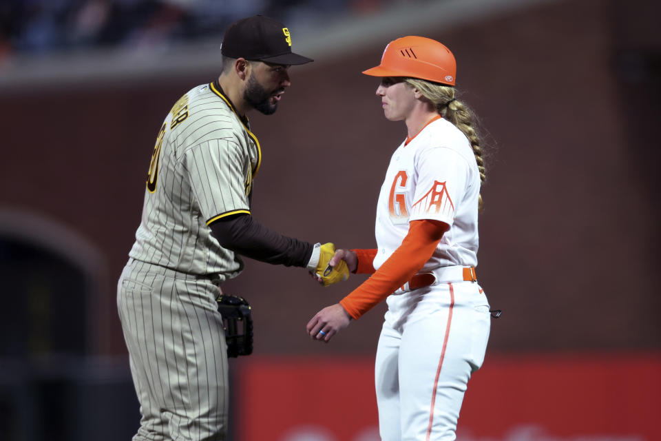 San Diego Padres first baseman Eric Hosmer, left, shakes hands with San Francisco Giants first base coach Alyssa Nakken during the third inning of a baseball game in San Francisco, Tuesday, April 12, 2022. (AP Photo/Jed Jacobsohn)